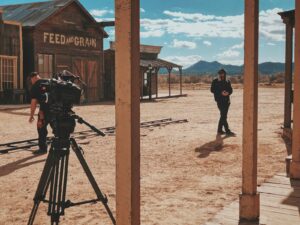 man in black jacket and pants standing in front of recording professional video camera